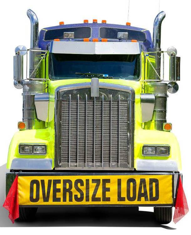Image of the front face of a semi truck, green incolor with a banner that reads "oversized load"
